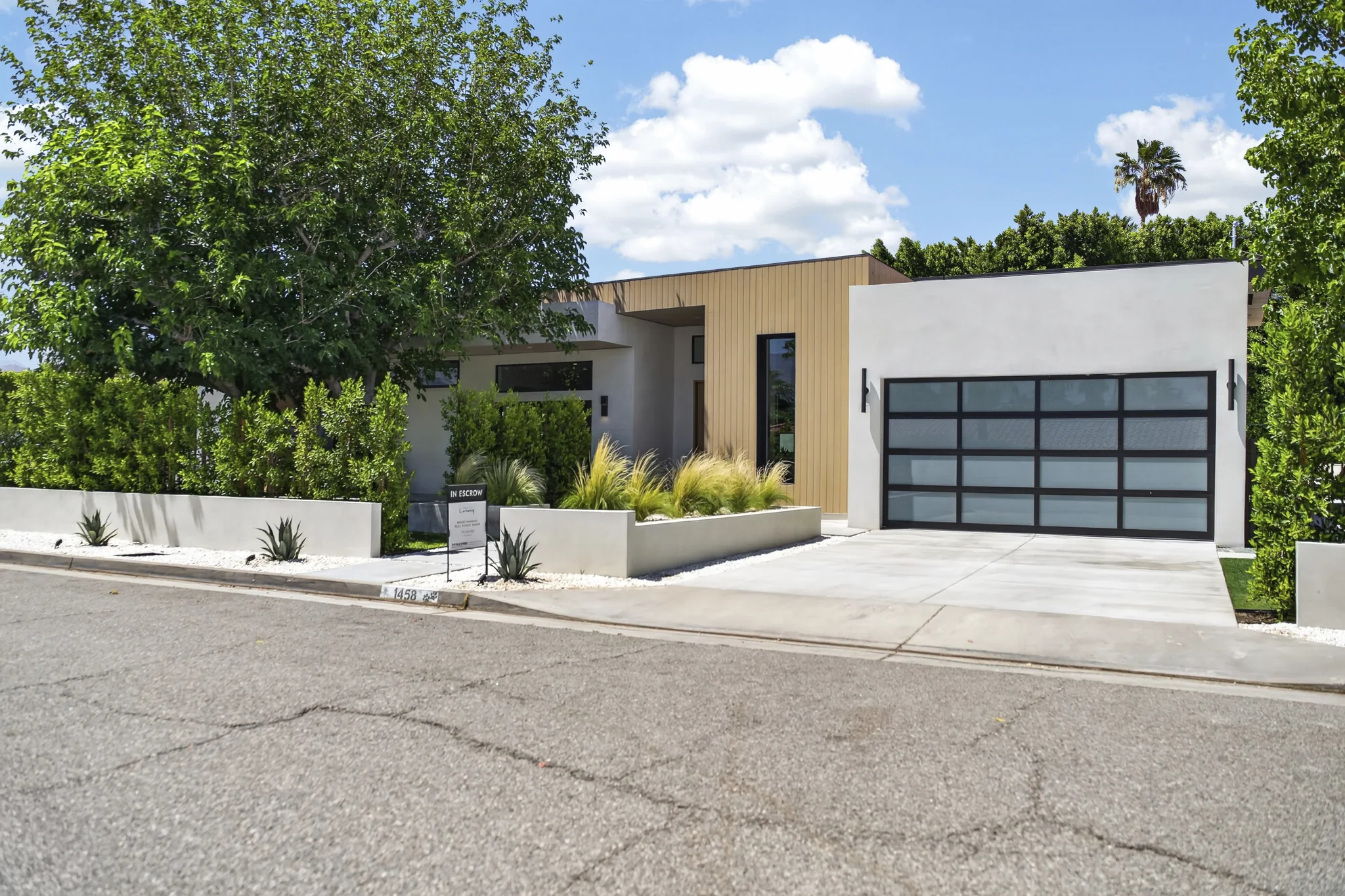 Alameda: street elevation with timber cladding, a glazed garage door and planted front garden