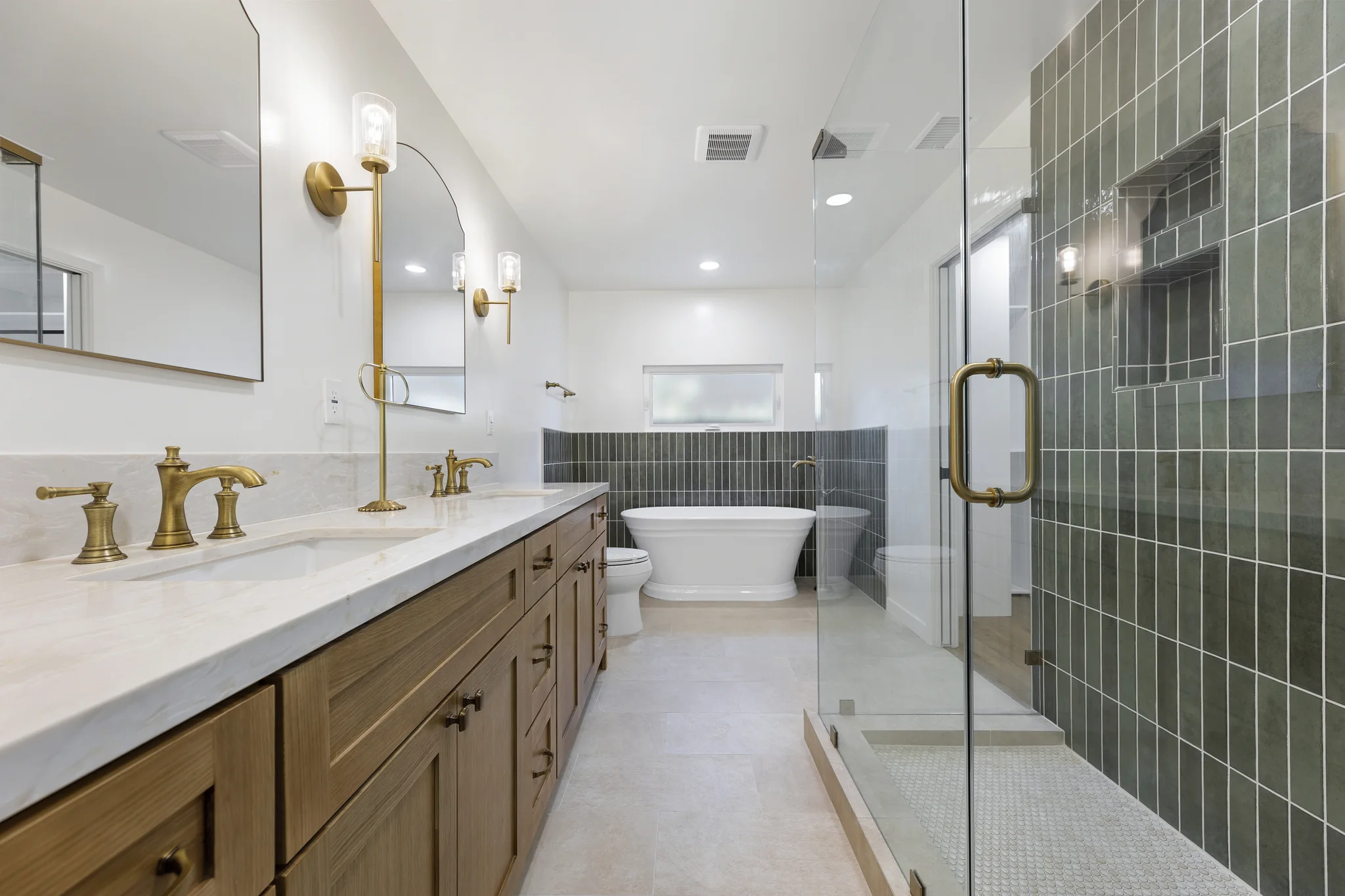 Álvarez: bathroom with twin basins, arched mirrors and green shower tile