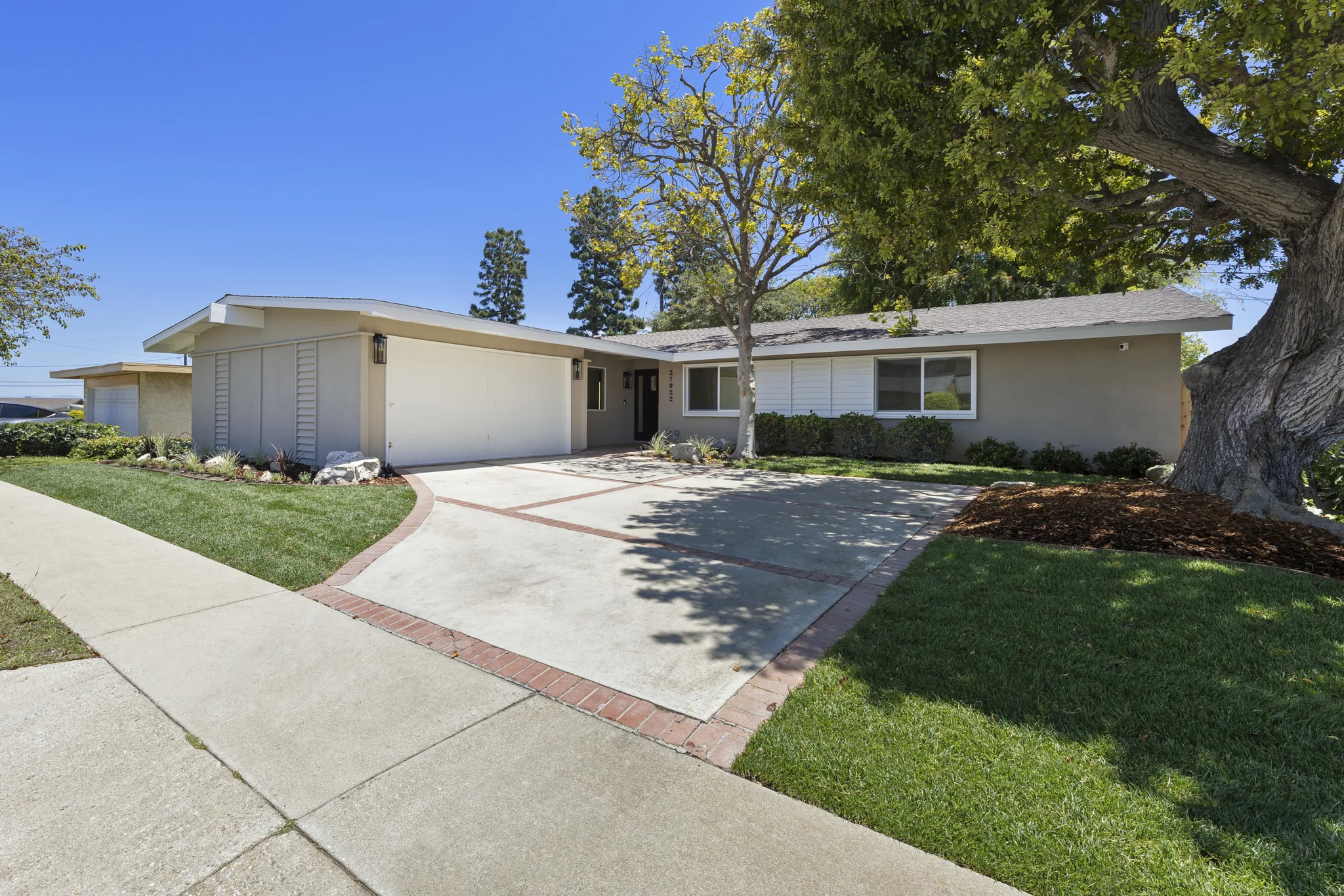 Álvarez: front elevation with lawn, mature tree and driveway