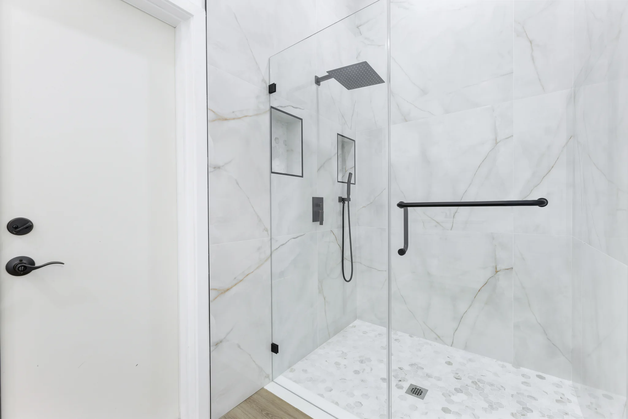 Conata: shower detail with dark fittings and pale stone-patterned walls