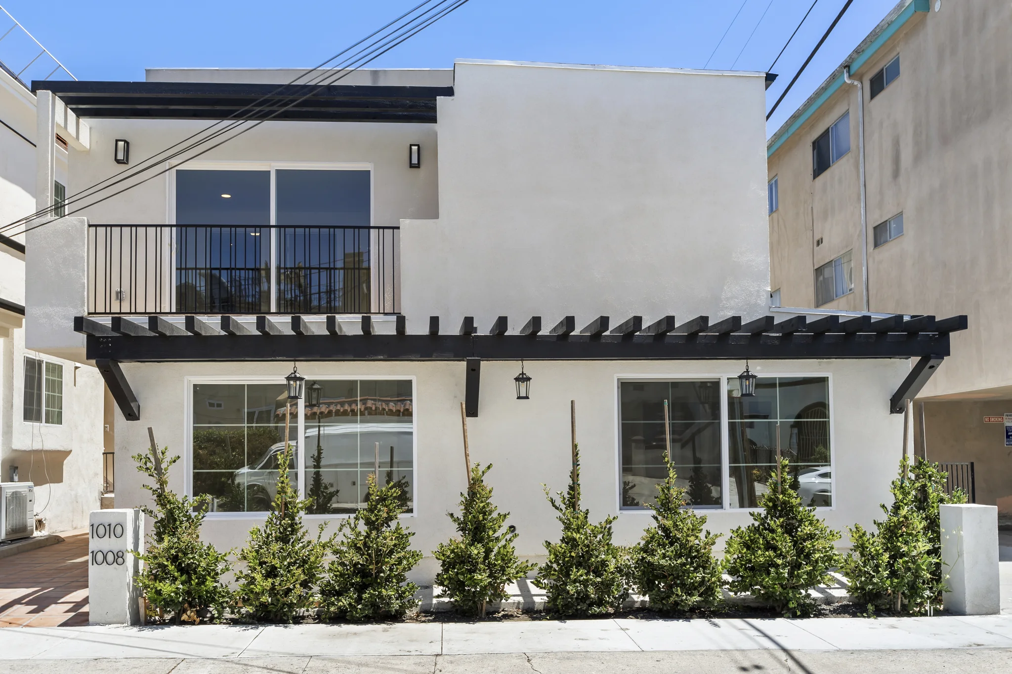 Sherbourne: street elevation with pale walls, dark pergolas and an upper balcony